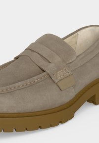 Ανοιχτό καφέ loafer από σουέντ με χοντρή λαστιχένια σόλα, λουράκι με penny και ορατό ράψιμο κατά μήκος της μύτης και των πλευρών.