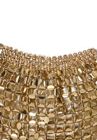 Bolso de mano tejido en oro con piezas metálicas ovaladas y redondas, textura suave y un ribete de cuentas a lo largo del borde superior.
