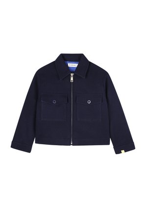 Veste zippée bleu marine avec col, deux poches à rabat à l'avant avec boutons, manches longues et une petite étiquette jaune sur le poignet.