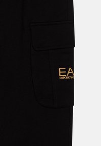 Schwarze Cargo-Shorts mit einer Klappentasche und goldenen "EA"-Logo, aus Baumwolle mit einer weichen, glatten Textur.