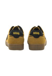 Gelbe Sneakers mit einer Wildleder-Textur, die schwarze Akzente und ein Logo auf der Rückseite haben. Gummisohle mit einem sportlichen, niedrig geschnittenen Design.
