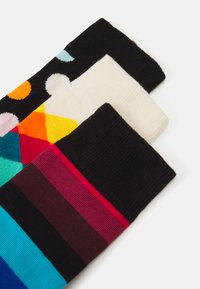 Chaussettes colorées arborant des motifs géométriques, des rayures et des pois. Les matériaux semblent doux avec une texture tricotée dans diverses couleurs, dont le noir, le blanc et le bleu.