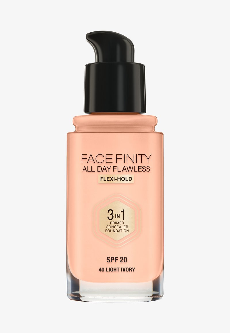 Pumpeflaske med foundation i lys elfenbenfarve, med sort låg og ferskenfarvet base. Indeholder SPF 20 og er mærket som 3-i-1 primer, concealer, foundation.