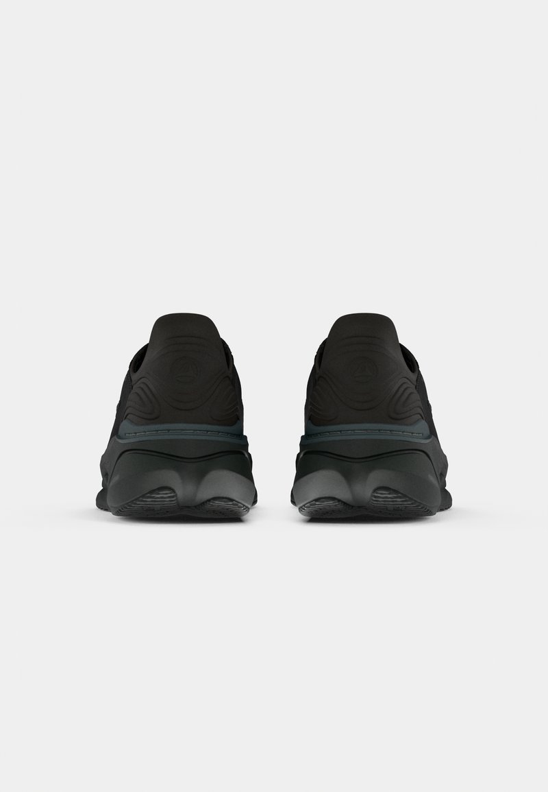 Paire de chaussures de sport noires vues de dos sur un fond blanc uni.