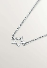 Collar de color plateado con un colgante en forma de estrella con centro abierto, diseño de cadena enlazada y acabado pulido.