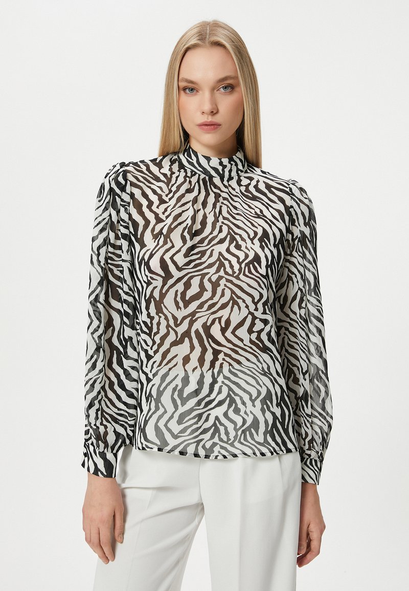 Durchsichtige Bluse mit schwarz-weißem Zebra-Print, langen Ärmeln, hohem Kragen und gerafften Manschetten, konzipiert mit einem leicht lockeren Schnitt.