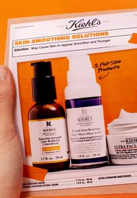 Kiehl's ihonhoitoluettelo sisältää kolme tuotetta: ruskea pullo mustalla pumppulla, valkoinen pullo purppuratäplällä ja kerma-astia, kaikki oranssilla taustalla.