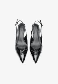 Svarta läder slingback-klackar med spetsig tå, prydda med en rosett vid framfoten och en slät, smidig yta. Minimalistisk design.