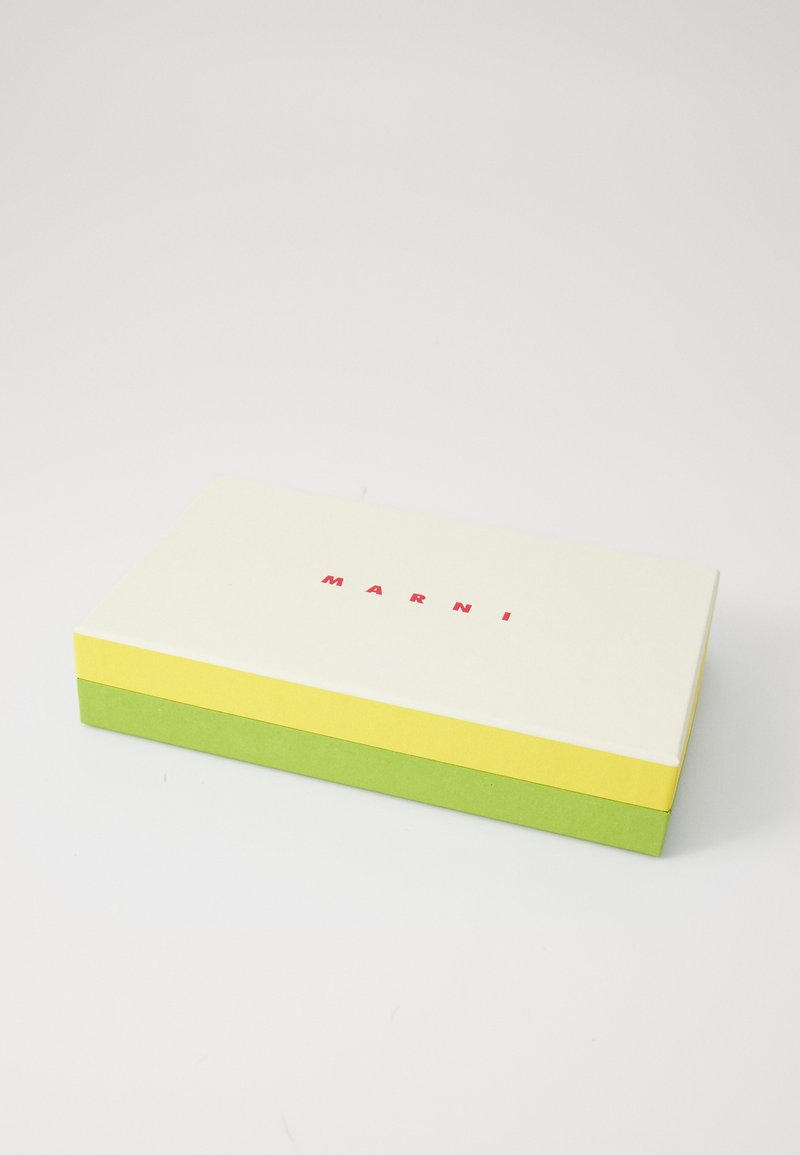 Scatola rettangolare con coperchio crema e lati verde e giallo. La parola "MARNI" in rosso è centrata sul coperchio. Texture liscia, design minimal.