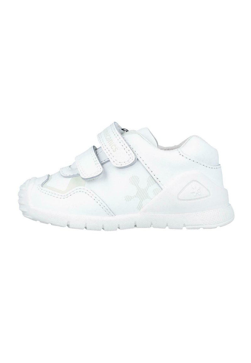 Zapatilla blanca con doble tira de Velcro, superficie sintética suave, cuello acolchado, suela texturizada y un sutil detalle del logo cerca del talón.