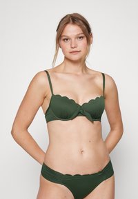 Conjunto de biquini verde com um design texturizado, bordas recortadas, alças ajustáveis e um detalhe frontal amarrado no sutiã. A parte debaixo tem um estilo correspondente.