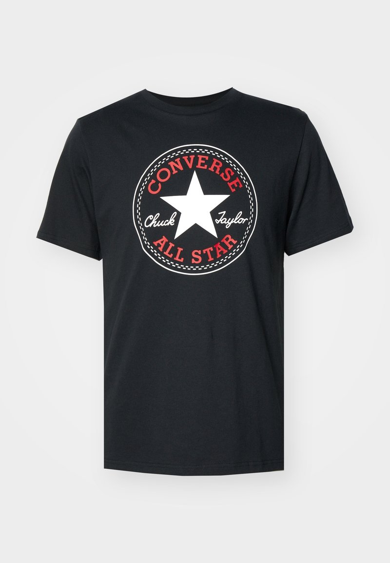 T-shirt noir avec une grande étoile blanche et un texte rouge et blanc indiquant "Converse Chuck Taylor All Star" à l'avant.