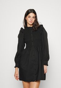 Rochie neagră cu un corset smockat, închidere cu nasturi în față și mâneci lungi tip puff cu detalii ondulate. Material ușor, cu o croială lejeră.