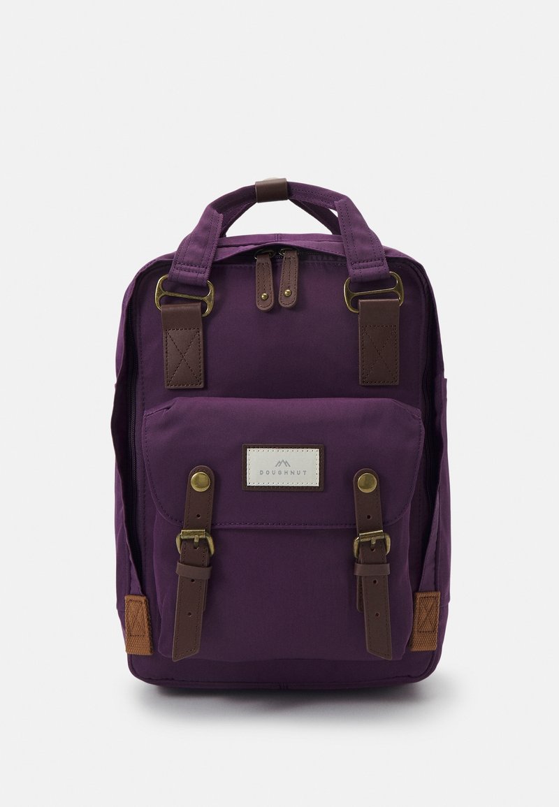 Purple canvas backpack with brown leather accents, dual top handles, front pocket, and buckle closures. Features a logo patch on front.