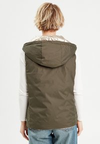 Gilet rembourré vert olive avec capuche et doublure argentée brillante. Présente un design simple et une coupe droite, fabriqué à partir d'un tissu texturé.