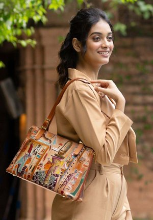 Tan leren handtas met gedetailleerd Egyptisch patroon in levendige kleuren; voorzien van schouderriem en gouden hardwareaccenten.