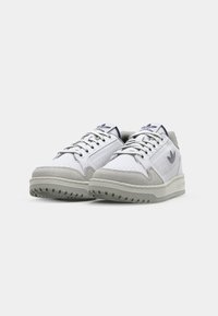 Zapatillas blancas con detalles en gamuza gris, lados perforados, cordones redondos y una suela de goma con patrones de tracción únicos.