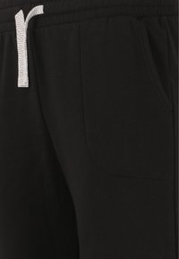 Svarta sweatpants av mjukt tyg, med en dragsko med zick-zack-mönster, sidofickor och resårmidja.