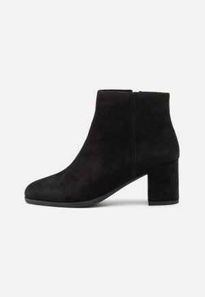 Bottines en daim noir avec un bout effilé, un talon bloc de hauteur intermédiaire et une texture lisse. Présente une couture subtile sur le côté.