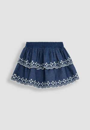 Denim svārki ar vairākiem slāņiem un gumijotu jostasvietu, pigmentā tumši zila krāsa, balti ziedu izšuvumi pie apakšmala un viļņota apmale.