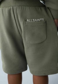 Oliveväriset shortsit pehmeästä kankaasta; takataskussa valkoisella kirjailtu "ALLSAINTS". Venyvä vyötärönauha.