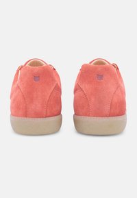 Coral suede sneakers with smooth beige rubber soles, featuring a subtle logo and round heel design. Back view highlights stitching details.