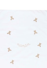 Tessuto bianco con otto ricami di orsetti di peluche beige e la parola "nanán" cucita in corsivo beige al centro.