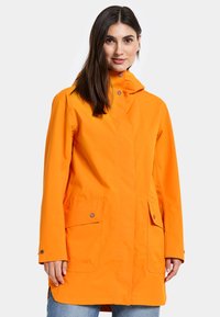Orange vattentät jacka med huva, med rak skärning, tryckknappstängning fram och två sidofickor. Slät textur, avslappnad design.