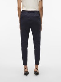 Pantaloni cu talie elastică de culoare bleumarin, cu croială conică, având două buzunare în spate și textură netedă, asortați cu sandale cu toc negre.