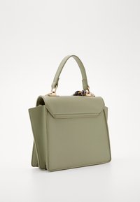 Bolso de mano verde salvia en material suave, con un diseño de solapa plegada, herrajes dorados y un asa corta para llevar.