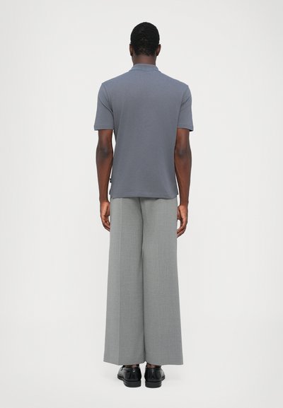 Gray polo shirt with short sleeves, paired with wide-leg light gray trousers, and black shoes. Smooth fabric with a clean design.