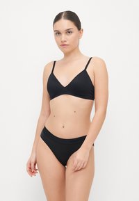 Zwarte bikini set met een driehoekige bralette met dunne bandjes en bijpassende high-waisted slipjes. Gemaakt van soepel, rekbaar materiaal.