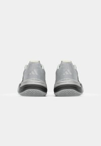 Graue Sportschuhe mit einer glatten Oberfläche, schwarzen Akzenten, strukturiertem Sohle mit Profilmuster und einem gepolsterten Fersenbereich.