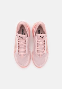 Zapatillas deportivas de color rosa claro, con materiales de malla y sintéticos, que cuentan con una lengüeta acolchada, cordones y una suela de goma texturizada con clavos.