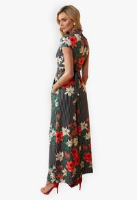 Floral maxi dress with a black and white striped pattern, short sleeves, side pockets, and a tie at the waist. Accented with red flowers.