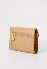 Tan leren portefeuille met een gestructureerde afwerking, een ritszakje aan de voorkant met goudkleurige hardware en een beknopt logo dat aan de voorkant is geperst.