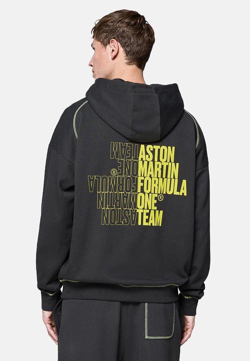 Czarna bluza z kapturem z dużą grafiką w kolorze żółtym na plecach. Posiada zielone przeszycia, kaptur na sznurki oraz luźny krój.