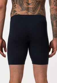 Tmavě modré, přiléhavé boxerky vyrobené z bavlny, s hladkým povrchem a elastickým pasem, zobrazené zezadu.