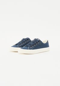 Marina canvas sneakers med vita gummisulor, gyllene öglor och matchande snören. Har en slank design och en texturerad yta.