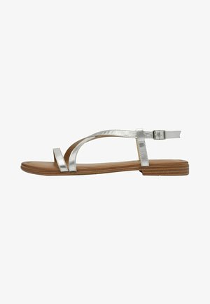 Sandali piatti metallici argento con un design minimalista, caratterizzati da due cinghie incrociate e una fibbia regolabile alla caviglia su una suola marrone.