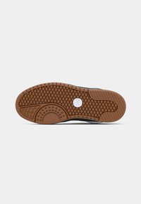 Shoe sole with a rubber bottom, featuring a herringbone pattern and circular accents. The color is brown with a black edge.