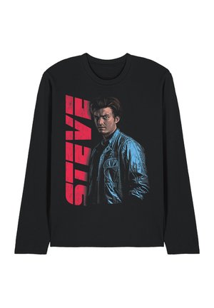 Schwarzes Langarmhemd mit einem ernsten jungen Mann in einer blauen Jacke und fettem roten senkrechtem Text "STEVE" neben ihm.