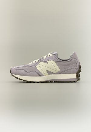 Baskets athlétiques violet clair et beige avec une semelle texturée et des lacets blancs, vues de profil sur un fond neutre.