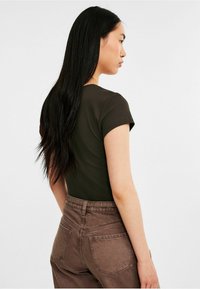 Haut marron à manches courtes côtelé associé à un pantalon en denim marron taille haute. Mettez l'accent sur la coupe ajustée et la douceur du tissu.