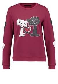 Bordowy sweatshirt z grafiką białego i czarnego kota w okularach przeciwsłonecznych, otoczonych kształtami serc na rękawach. Materiał z domieszką bawełny.