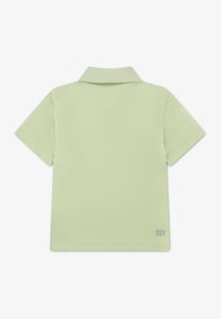 Πράσινο χλωμό πόλο μπλουζάκι με κλασικό γιακά, κοντά μανίκια και λεία υφή. Διαθέτει το λογότυπο "ULTRA DRY" κάτω δεξιά.