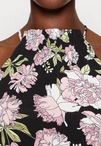 Top de tecido preto com um padrão floral de flores rosa e brancas, apresentando um decote franzido com alças finas.
