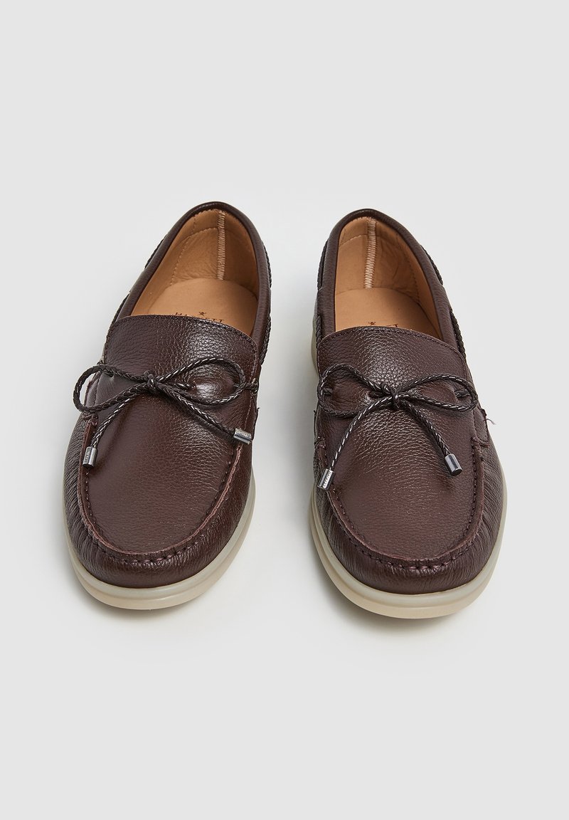 Mocassins en cuir brun avec une finition texturée, dotés de détails en dentelle décorative et d'une semelle en caoutchouc de couleur claire. Design à bout rond.