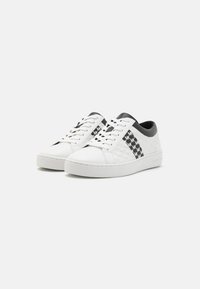 Sneaker bianchi con un motivo testurizzato e accenti neri. Presentano una tomaia in pelle liscia, chiusura con lacci e una suola imbottita.