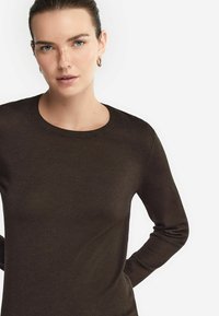 Brun långärmad tröja med rund hals. Slät textur, figurnära design och ribbade mudd. Minimalistisk stil utan synliga mönster eller detaljer.